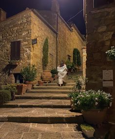 a woman is walking down some steps in an alley way at night with the light on