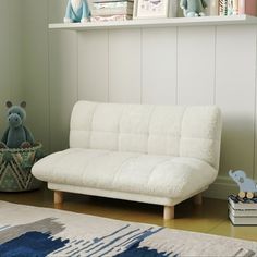 a white futon sofa sitting on top of a wooden floor next to a book shelf