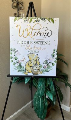 a welcome sign for a baby shower is displayed in front of a houseplant