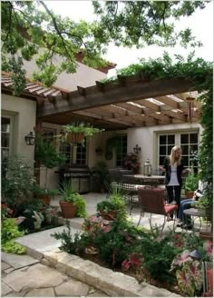 a woman standing in the back yard of a house next to a table and chairs