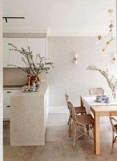 a dining room table and chairs in front of a counter with vases on it