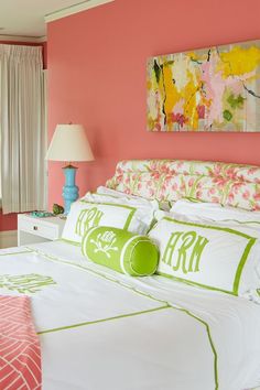 a bedroom with pink walls and white bedding, green accents on the headboard