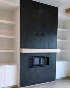 an empty living room with white shelves and black fireplace