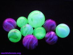 glow in the dark marbles are glowing green and purple on a black table top