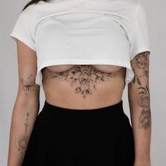 a woman with tattoos on her stomach and chest is wearing a white cropped t - shirt