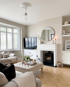 a living room filled with furniture and a flat screen tv mounted on the wall above a fire place