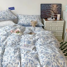 a bed with blue and white bedspread in a bedroom next to a dresser