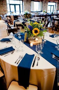 a table set with place settings and sunflowers in vases on the tables