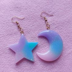 These adorable star and moon shaped earrings, you will receive a set that contains 1 moon and 1 matching star earrings. The charms are made out of resin. The image with the mesuringtool is in cm. Please note that the earrings hooks are not made out of sterling silver. I also offer these earrings with a clip on option, if you prefer a clip on earrings please add a note with your order stating you would prefer clip ons instead of hooks. Updated shipping information regarding the current situation. Cute Purple Dangle Jewelry, Cute Iridescent Earrings For Gift, Pink Kawaii Resin Jewelry, Pink Resin Kawaii Jewelry, Cute Purple Drop Earrings, Cute Handmade Star Jewelry, Trendy Purple Star-shaped Jewelry, Trendy Purple Star Shaped Jewelry, Handmade Blue Kawaii Jewelry