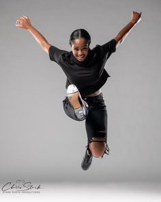 a woman is jumping in the air with her arms outstretched