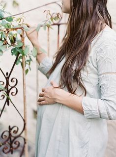 a woman standing next to a fence with her hands on the railing and looking down