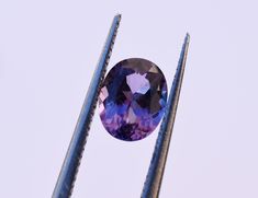 an oval shaped purple diamond sitting on top of two metal poles in front of a blue sky