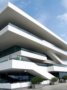 two people standing on the balcony of a large white building with many balconies