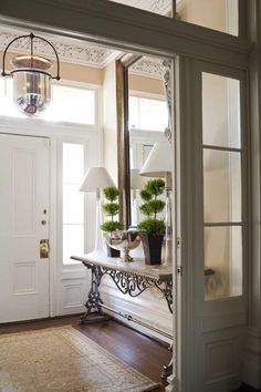 the front door is open to reveal an entryway with crown molding and pendant light