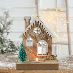 a small wooden house with a lit candle in front of it on top of a table