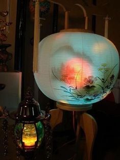 a lit up lamp sitting on top of a table next to a vase and lantern