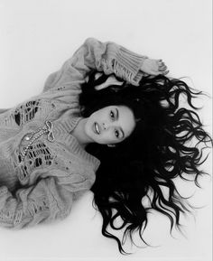 a black and white photo of a woman laying on the ground with her hair blowing in the wind