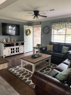 a living room filled with furniture and a flat screen tv mounted on the wall above a wooden coffee table