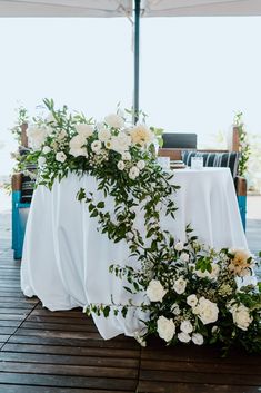 the table is covered with white flowers and greenery