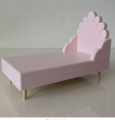 a pink doll bed sitting on top of a white floor next to a gray wall