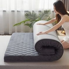 a woman sitting on the floor next to an inflatable mattress that is rolled up