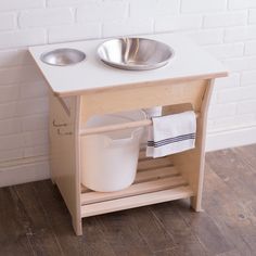 a wooden stand with two bowls and a metal bowl on it's shelf next to a white brick wall