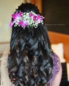 the back of a woman's head with flowers in her hair, wearing a purple dress