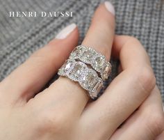 a woman's hand with two diamond rings on top of her finger and the words henri daussi above it