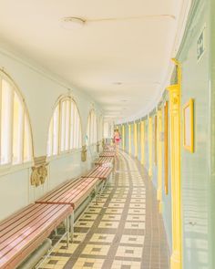 a long hallway with several benches lined up along the wall and windows on both sides