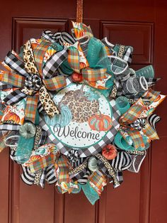 a welcome wreath hanging on a door with leopard, pumpkins and cheetah