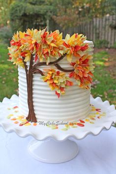 a white cake decorated with leaves and a tree