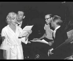 black and white photograph of marilyn monroe with two men in front of her, one man holding papers