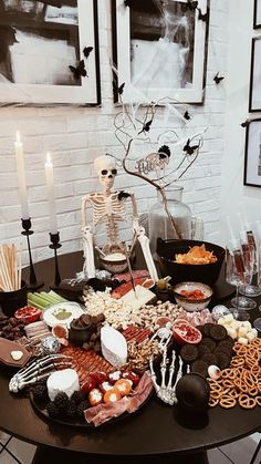 a table topped with lots of halloween food and candles in front of pictures on the wall