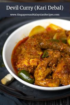 a white bowl filled with food on top of a black plate and topped with green peppers