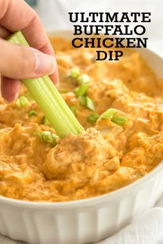 a person dipping some kind of food into a bowl with celery on top