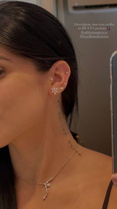 a woman is looking at her cell phone with piercings on her ear and holding it up in front of her face