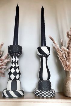 two black and white candles are on a shelf with other decorative items in front of it