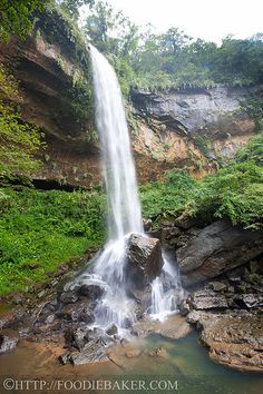 a large waterfall in the middle of a lush green forest