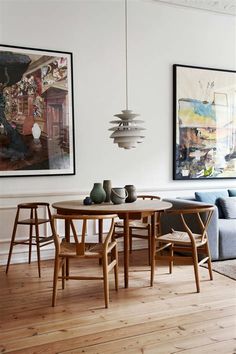 a living room filled with furniture and paintings on the wall next to a wooden floor