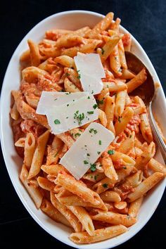 pasta with sauce and parmesan cheese in a white bowl on a black table