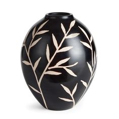 a black vase with white leaves on it