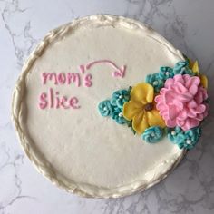 there is a cake that says mom's slice with flowers on the bottom and pink, blue, yellow and green icing