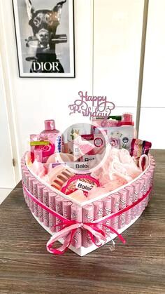 a pink heart shaped basket filled with lots of items on top of a wooden table