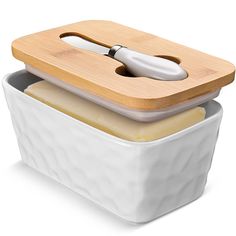 two white containers with wooden lids are stacked on top of each other and one has a spoon in it