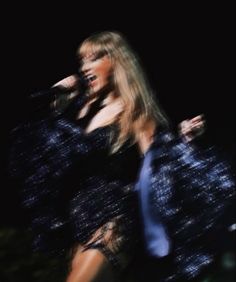 a woman with long hair wearing a black dress and blue tie is standing in front of a microphone