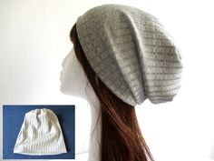 a woman's head wearing a white and gray knitted hat with long brown hair