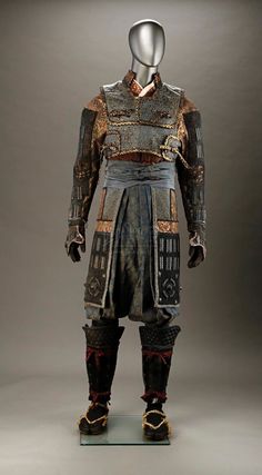 an elaborately decorated armor is displayed on a glass display stand in front of a gray background