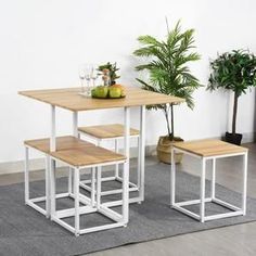 a table and two stools with fruit on it in front of a potted plant