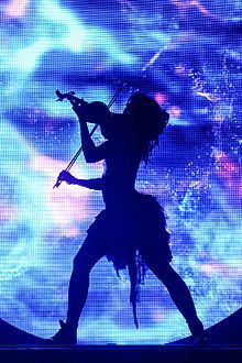 the silhouette of a woman on stage holding a microphone