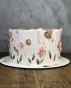 a white cake decorated with pink flowers and leaves